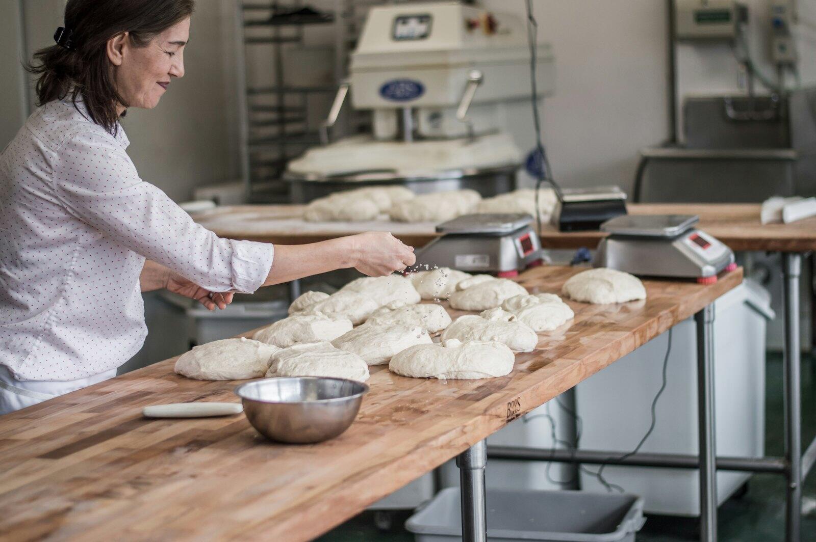Une boulangère façonne les pâtons sur le plan de travail
